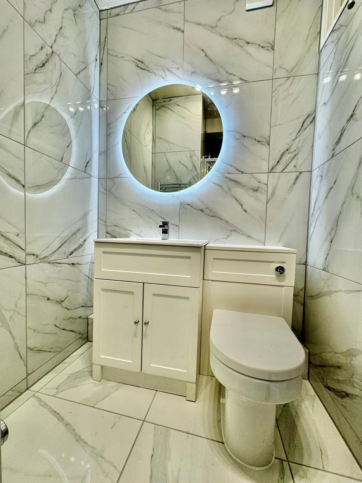 Austen Room ensuite bathroom with marble tiling and illuminated mirror